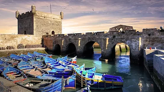 Essaouira harbor with blue fishing boats and fortified sea walls under an Atlantic sky